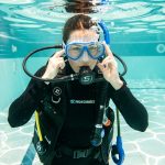 Une plongeuse s’exerce calmement à vider son masque dans une piscine d’entraînement aux eaux claires.