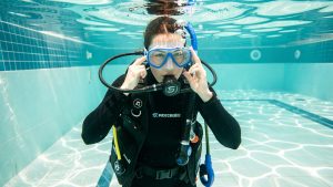 Une plongeuse s’exerce calmement à vider son masque dans une piscine d’entraînement aux eaux claires.